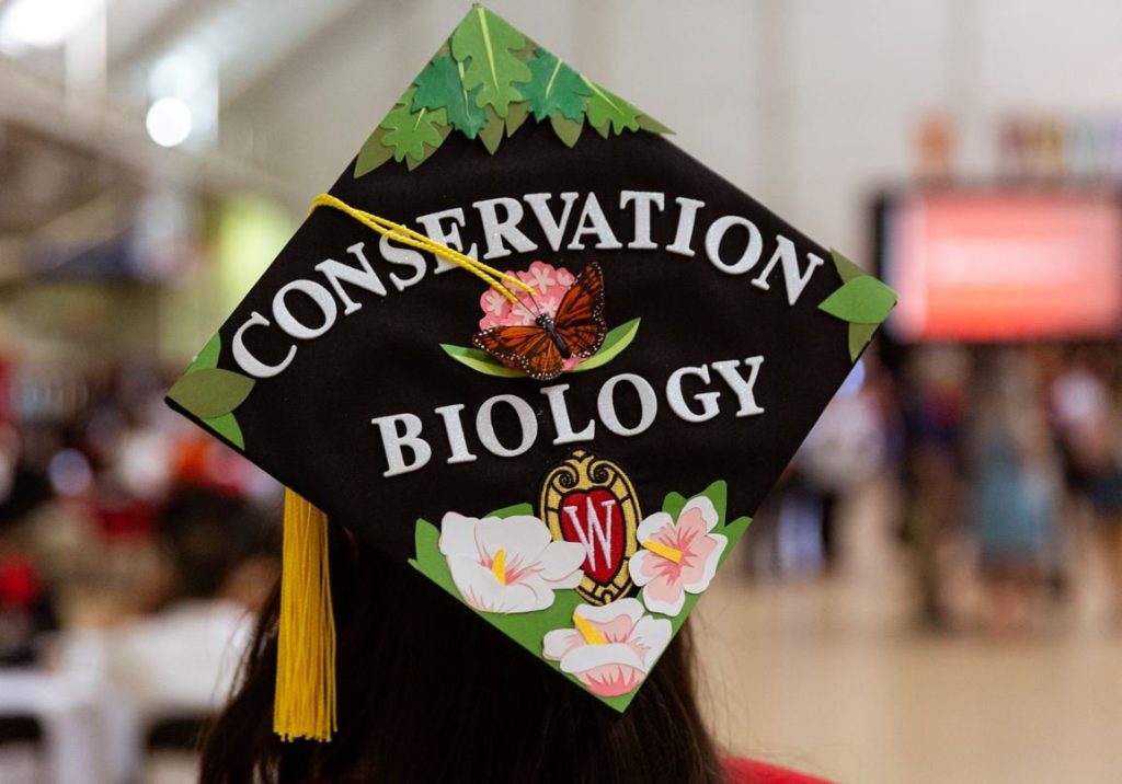 Graduation Mortar Board decorated with leaves, flowers and the words "Conservation Biology"